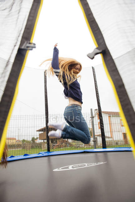 Sdaytimenatride vista de alegre menina loira pulando no trampolim — Fotografia de Stock