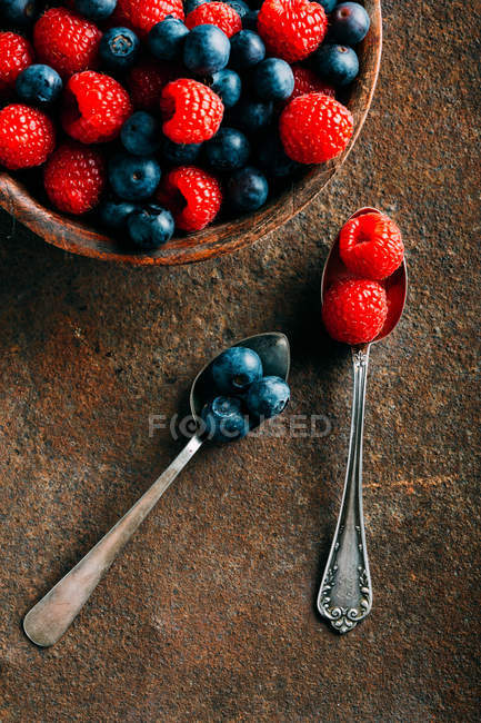 Blueberries and raspberries with vintage spoons — Stock Photo