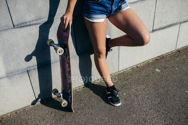 Cortar menina posando com skate velho — Fotografia de Stock