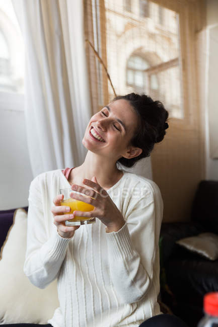 Porträt eines lächelnden Mädchens, das mit geschlossenen Augen und einem Glas Orangensaft auf einem Reisebus posiert — Stockfoto