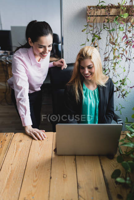 Portrait of woman looking at colleague laptop screen at workplace in office — Stock Photo