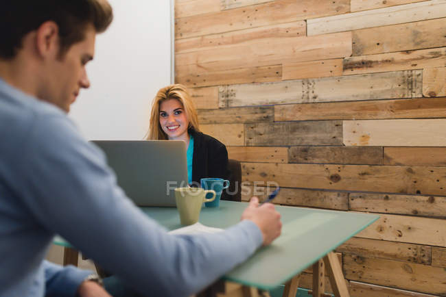 Retrato de mulher de negócios loira usando e olhando para a câmera sobre laptop no escritório moderno — Fotografia de Stock