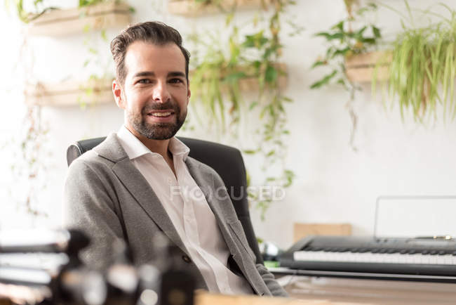 Homme barbu assis dans une chaise de bureau et regardant la caméra — Photo de stock