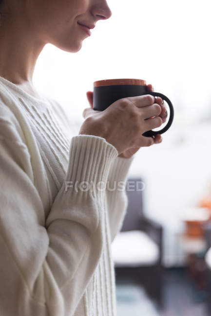 Ritaglia l'immagine della donna che sorride e tiene in mano una tazza con bevanda calda — Foto stock