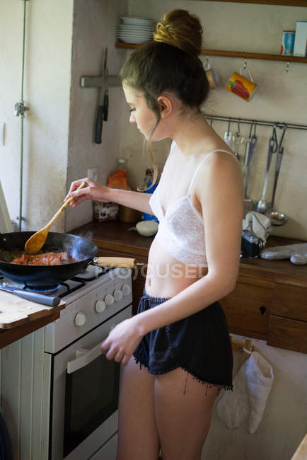 Chica cocinar y probar la comida - foto de stock