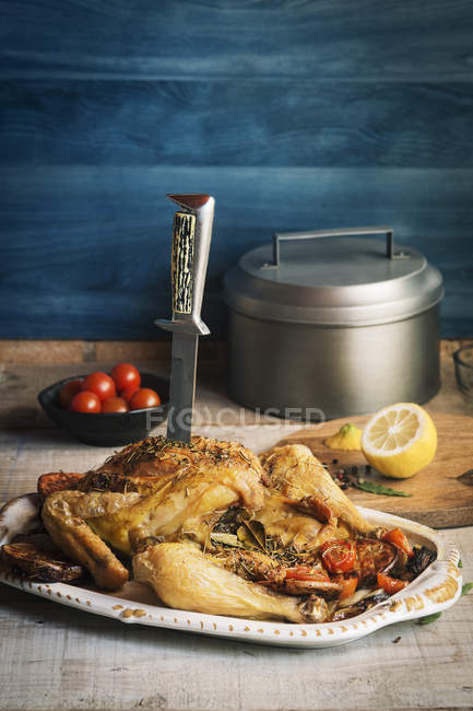 Roasted chicken with knife nailed — Stock Photo