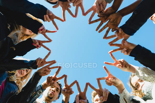 Офисные работники стоят в кругу и делают звезду жестом двух пальцев. — стоковое фото