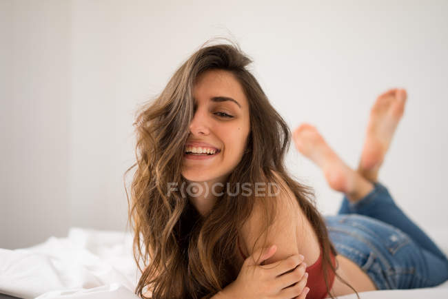 Brune joyeuse posant sur le lit — Photo de stock