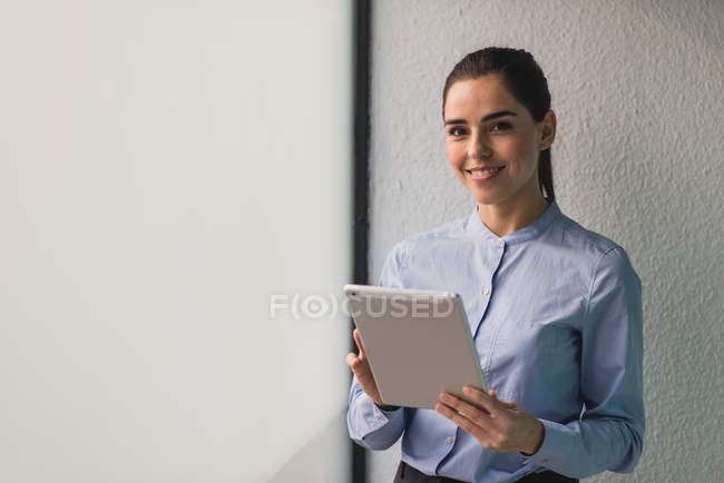Porträt eines brünetten Mädchens, das mit Tablet am Fenster steht und in die Kamera schaut — Stockfoto