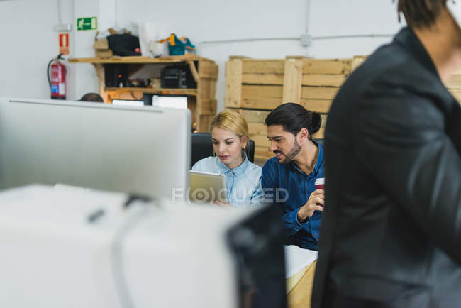 Crop office scene of employees browsing tablet at workplace — Stock Photo