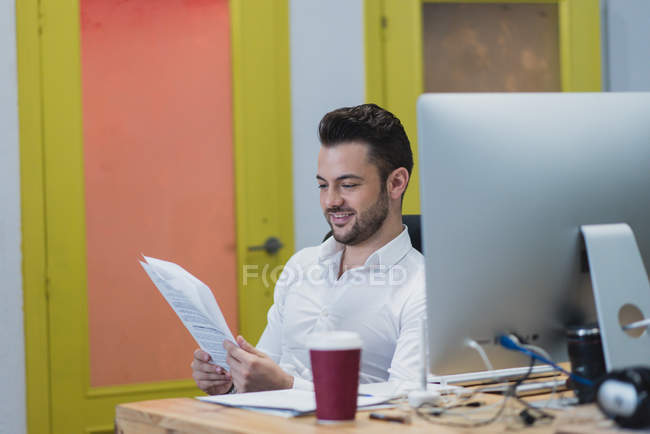 Ritratto di impiegato seduto al tavolo dell'ufficio e documenti di lettura . — Foto stock