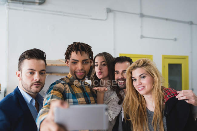 Portrait of group of business people taking selfie with smartphone camera in office. — Stock Photo