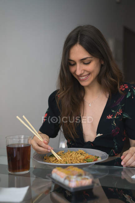 Улыбающаяся девушка ест лапшу — стоковое фото