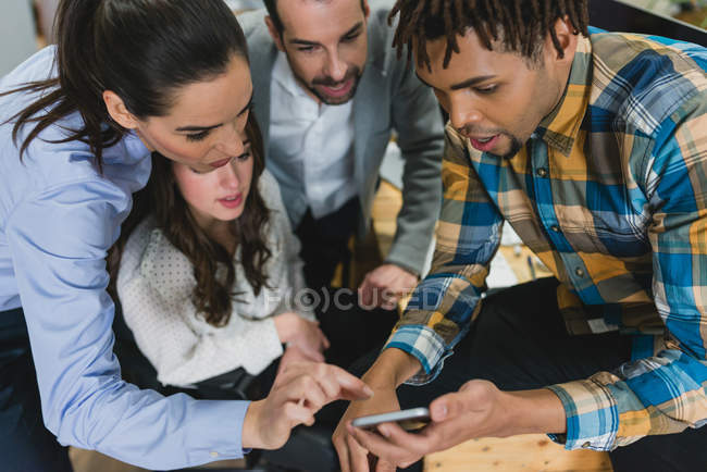 Man showing information on screen of smartphone to team — Stock Photo