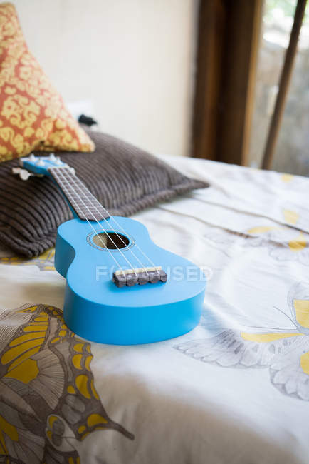 Голубая гитара, лежащая на кровати — стоковое фото