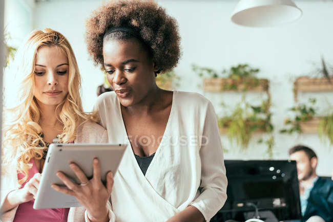 Businesswomen browsing tablet at modern office — Stock Photo