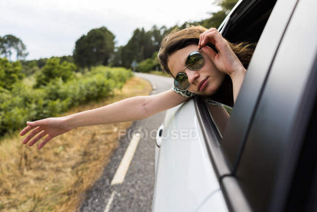 Smiling young woman looking out of sunroof of a car stock photo