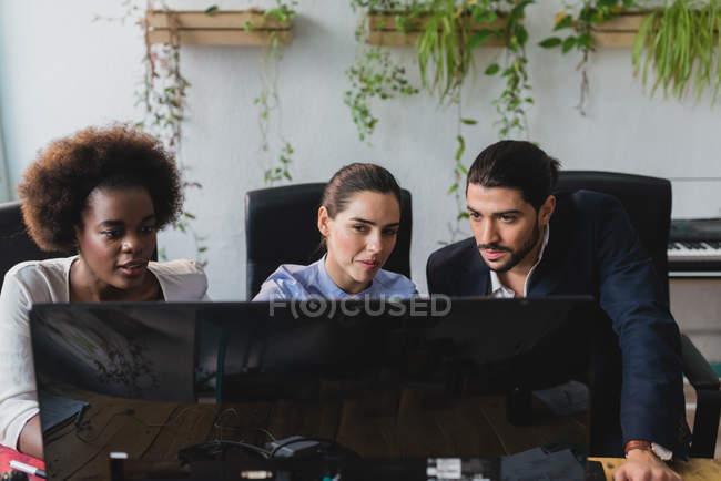 Портрет офисной команды, смотрящей на экран компьютера в офисе — стоковое фото