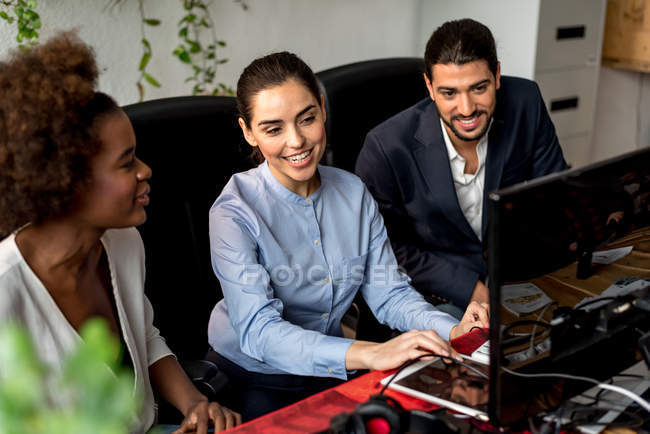 Cheerful colleagues looking at monitor in office — Stock Photo