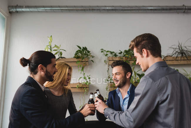 Side view of group of colleagues drinking beer after working time in office. — Stock Photo