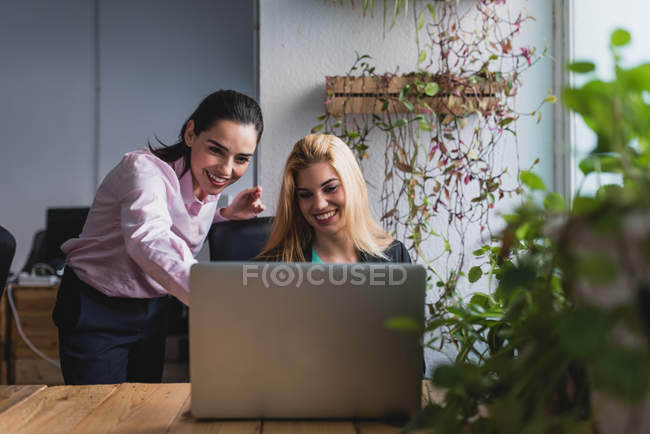 Ritratto di donna che punta al collega sullo schermo del computer portatile sul posto di lavoro in ufficio — Foto stock