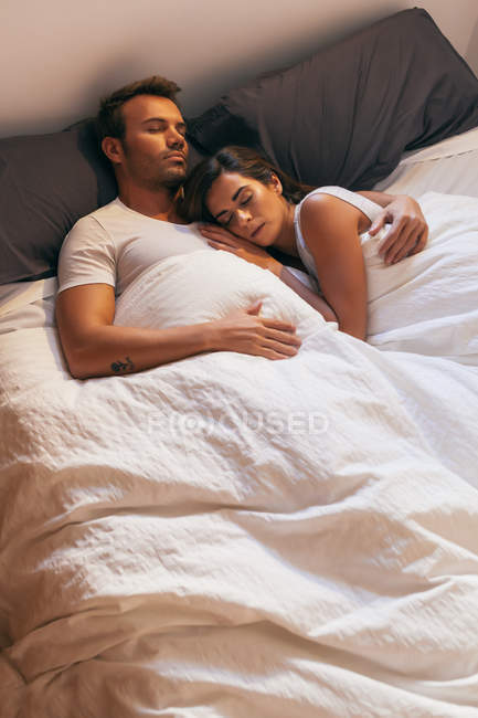 Jeune couple dormant au lit — Photo de stock