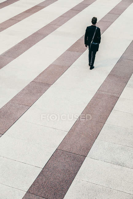 Homme d'affaires marchant à travers le plancher dépouillé — Photo de stock