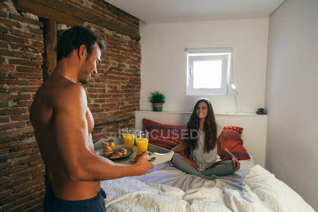 Schöner Mann bringt Frühstück ins Bett — Stockfoto