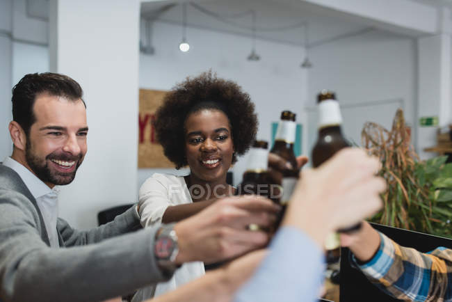 Portrait of people clanging bottles in office while teambuilding — Stock Photo