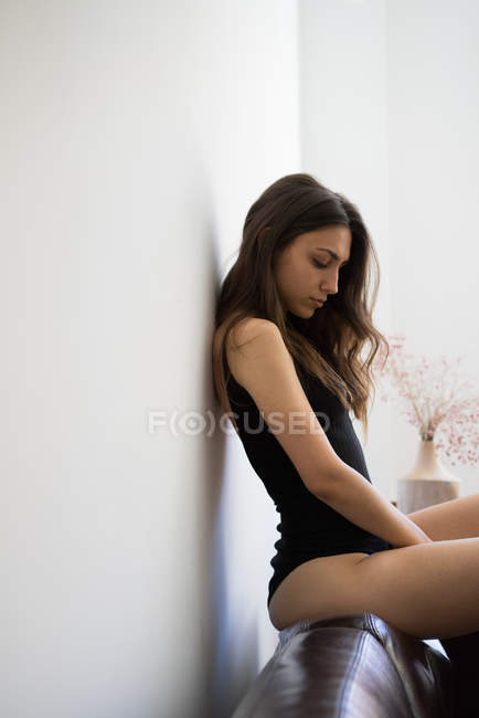 Ніжна дівчина в боді-костюмі сидить на дивані — стокове фото