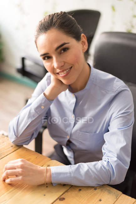 Brunette businesswoman at workplace cheerfully  looking at camera — Stock Photo