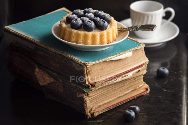 Blueberries cake over old books — Stock Photo