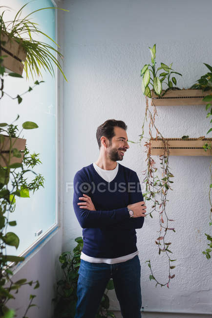 Portrait of man standing near window with hands crossed and looking aside — Stock Photo
