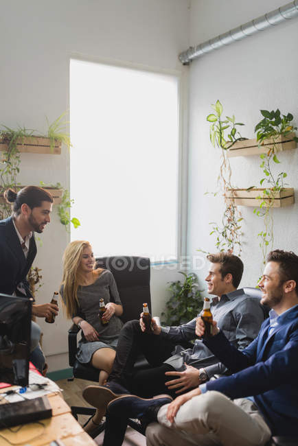 Side view of group of colleagues drinking beer after working time in office. — Stock Photo