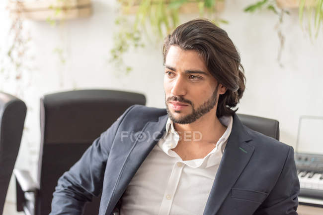Confident businessman sitting in office and looking away — Stock Photo