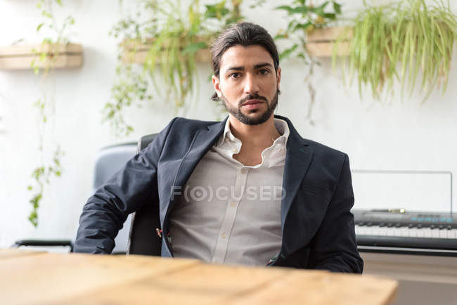 Confident businessman sitting at office and looking at camera — Stock Photo