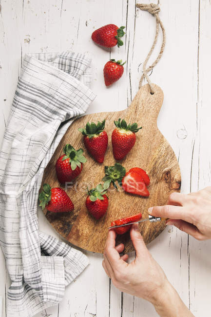 Manos de mujer cortando fresas - foto de stock