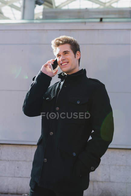 Portrait of man talking phone over grey wall at street — Stock Photo