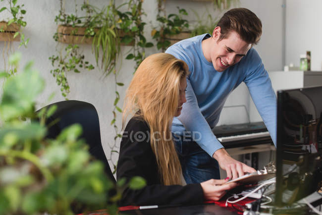 Vista laterale dell'uomo sorridente che indica un collega al tablet nelle sue mani sul posto di lavoro dell'ufficio — Foto stock