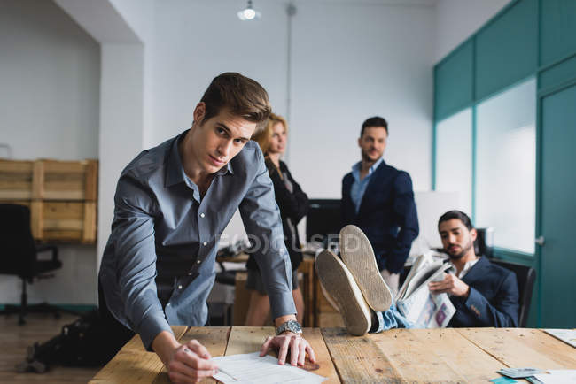 Portrait of businessman signing papers and looking at camera at modern office — Stock Photo