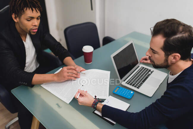 Dos hombres de negocios sentados a la mesa y discutiendo los documentos. Tiro de estudio horizontal. - foto de stock