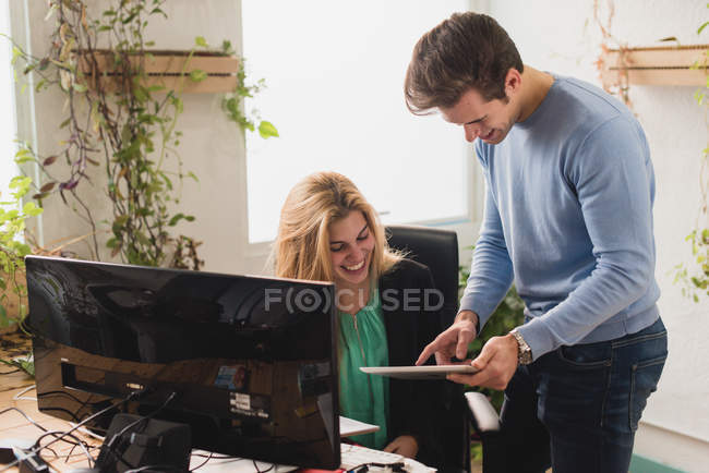 Porträt lächelnder Kollegen, die am Tisch im Büro mit dem Tablet surfen — Stockfoto