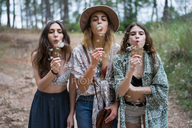 Three girls blowing dandelions — Stock Photo