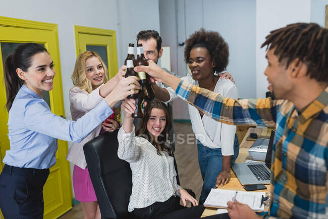 Trabalhadores de escritório felizes batendo garrafas com cerveja. Horizontal dentro de casa tiro. — Fotografia de Stock