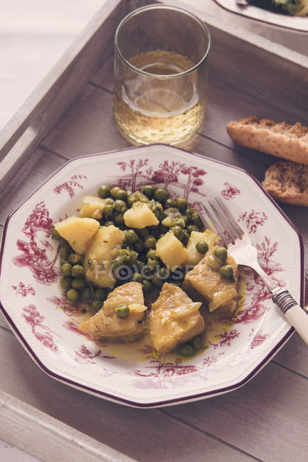 Hake in sauce with potatoes and peas — Stock Photo
