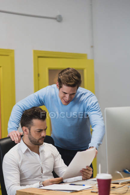 Portrait of colleagues at desk and looking through documents in office. — Stock Photo