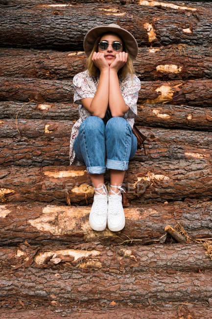 Trendfrau posiert auf Holzstämmen — Stockfoto