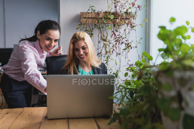 Ritratto di donna d'affari che punta al collega sullo schermo del computer portatile — Foto stock