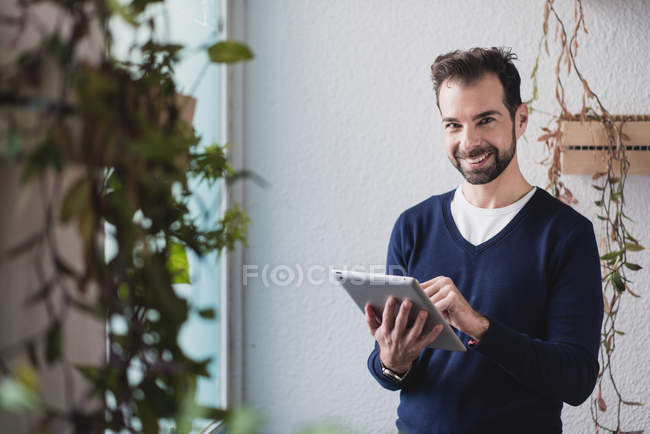 Retrato del hombre sonriente usando la tableta y mirando a la cámara - foto de stock