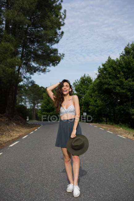 Jeune femme souriante sur la route rurale — Photo de stock